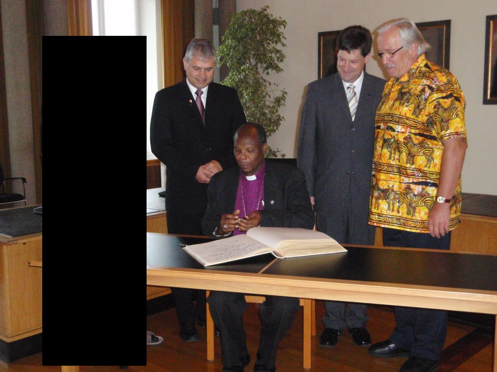 Bishop Kahuthu signed the visitors' book of the city of Freudenstadt (in the background from left to right:  Chairman of Foerderkreis Kenia e.V. (removed from image following a request of his heirs), Dean Harald Stumpf, Mayor Osswald and Mr. Dieter of Foerderkreis Kenia e.V.)